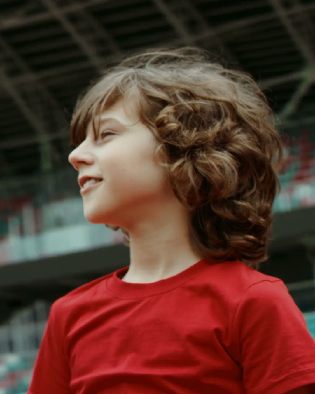 Children playing football: a boy smiles in a stadium, a girl cheers after a goal, a team hugs.