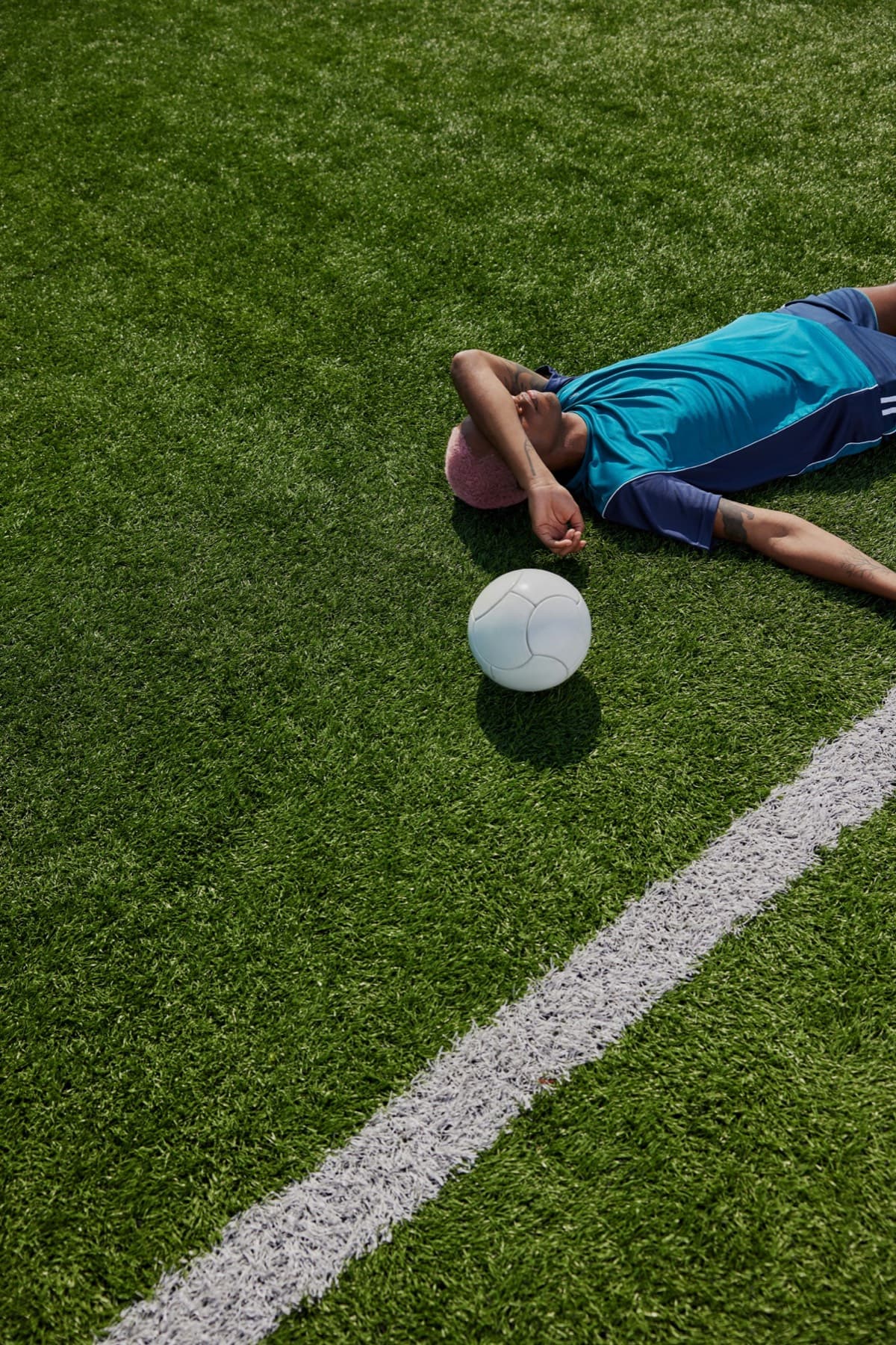 A player lies alone on the pitch next to the ball