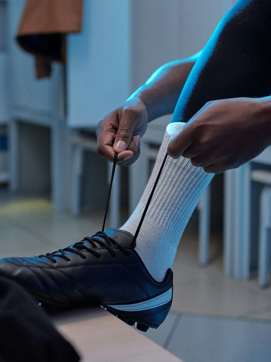 A player laces his football boot alone in the dressing room