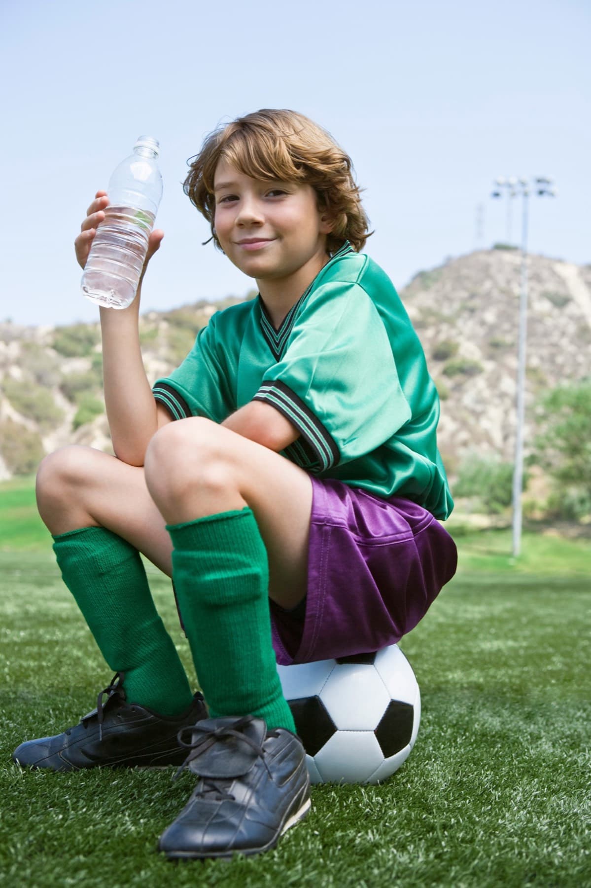 A boy sits on a ball with a water bottle